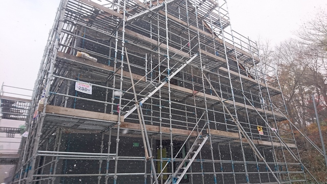 雪の中、ブラック系のサイディング工事（４００平米）を実施中の様子。